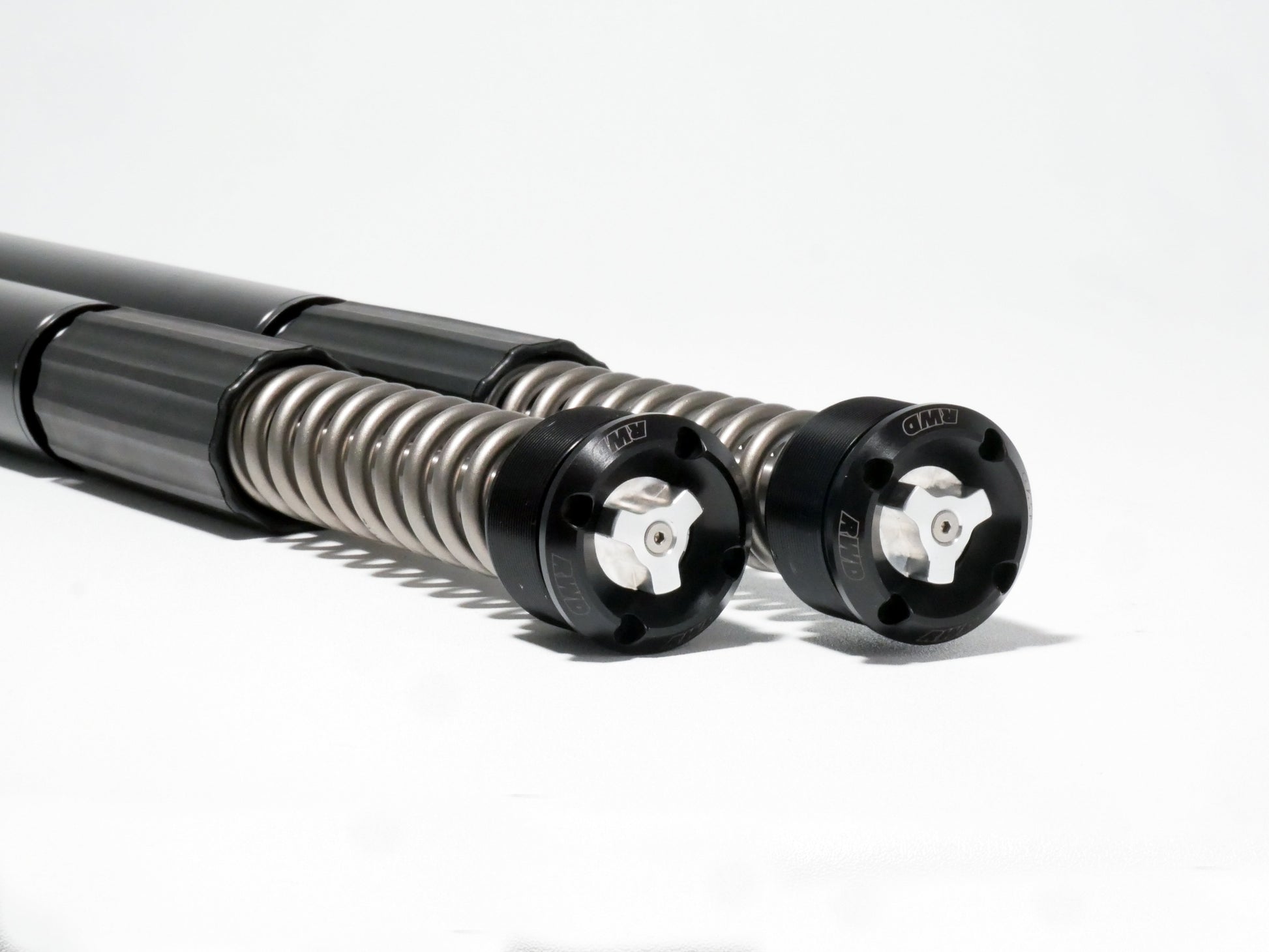 Two RWD V-Twin motorcycle fork cartridges with exposed springs and black adjustable caps, featuring the RWD logo, on a white background.